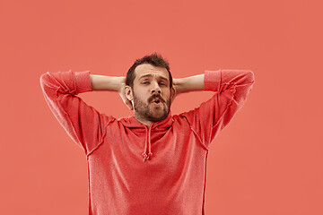 Image showing Beautiful man looking suprised and bewildered isolated on coral