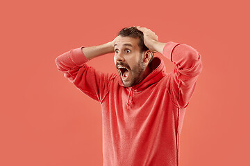 Image showing The young emotional angry man screaming on coral studio background