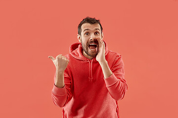 Image showing The young attractive man looking suprised isolated on coral