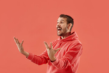 Image showing The young attractive man looking suprised isolated on coral