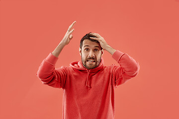 Image showing Beautiful man looking suprised and bewildered isolated on coral