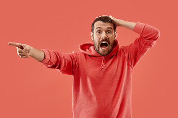 Image showing The young emotional angry man screaming on coral studio background