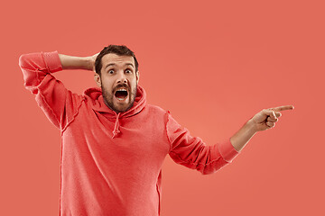 Image showing The young attractive man looking suprised isolated on coral