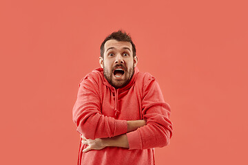 Image showing Beautiful man looking suprised and bewildered isolated on coral