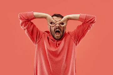 Image showing The squint eyed man with weird expression isolated on coral