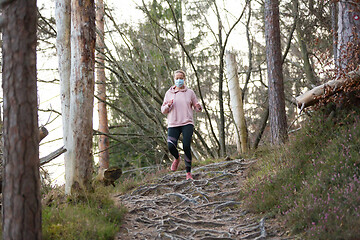 Image showing Corona virus, or Covid-19, is spreading all over the world. Portrait of caucasian sporty woman wearing a medical protection face mask while running in nature.