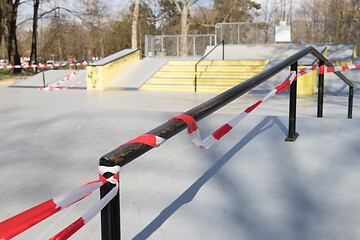 Image showing Corona virus COVID-19 restriction. No people due to quarantine. Closed urban skate park. Empty park and playground. Stay at home compaign. Red warning tape on ramps and slides. Social distancing