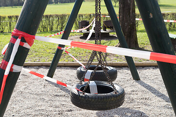 Image showing Corona virus COVID-19 restriction. No people due to quarantine. Closed urban park. Empty park and playground. Stay at home compaign. Red warning tape on ramps and slides. Social distancing