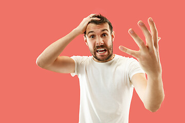 Image showing Beautiful man looking suprised and bewildered isolated on coral