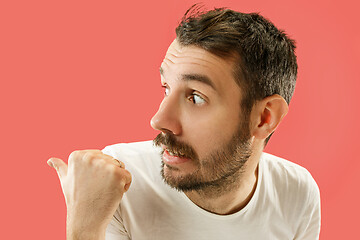 Image showing The young man whispering a secret behind her hand over coral background