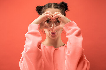 Image showing Portrait of attractive cute girl with bright makeup with love isolated over coral background