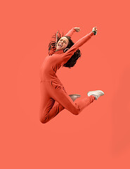 Image showing Freedom in moving. Pretty young woman jumping against coral background