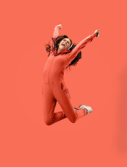 Image showing Freedom in moving. Pretty young woman jumping against coral background