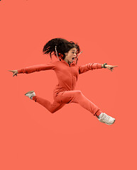 Image showing Freedom in moving. Pretty young woman jumping against coral background