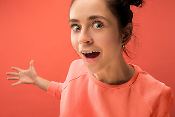 Image showing Beautiful woman looking suprised isolated on coral