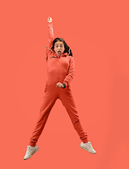 Image showing Freedom in moving. Pretty young woman jumping against coral background