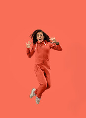 Image showing Freedom in moving. Pretty young woman jumping against coral background