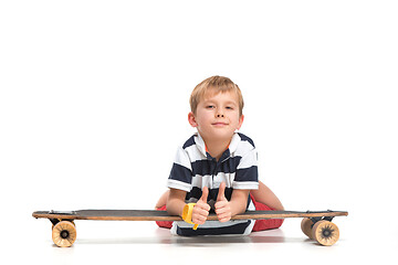 Image showing Full length portrait of an adorable young boy riding a skateboard isolated against white background