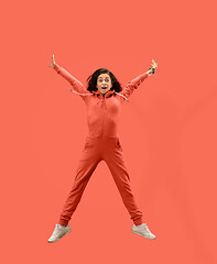 Image showing Freedom in moving. Pretty young woman jumping against coral background