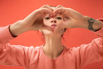 Image showing Portrait of attractive cute girl with bright makeup with love isolated over coral background