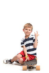 Image showing Full length portrait of an adorable young boy riding a skateboard isolated against white background