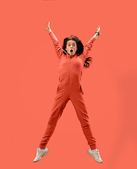 Image showing Freedom in moving. Pretty young woman jumping against coral background