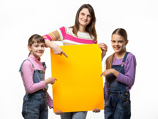 Image showing Mom and two daughters hold an orange sign in their hands and point to it