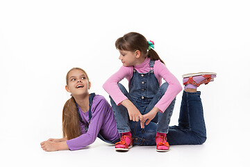 Image showing Two sisters play against a white background in denim jumpsuits