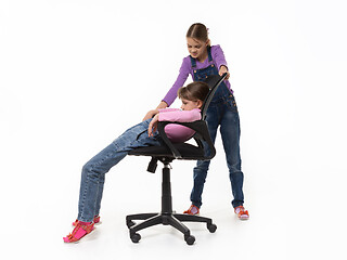 Image showing Girl offended by sister sliding off chair on a white background