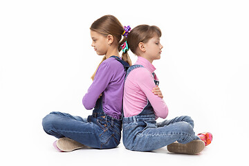 Image showing Two quarrelled girls sit with their backs to each other on a white background