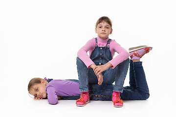 Image showing Two sad girls rest sitting and lying on a white background