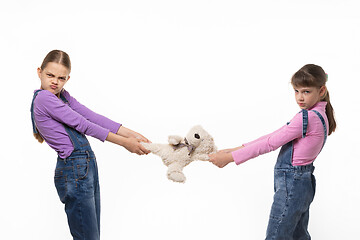 Image showing Two disgruntled sisters share a toy on a white background