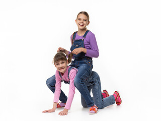 Image showing Two sisters play jockey and horse against a white background