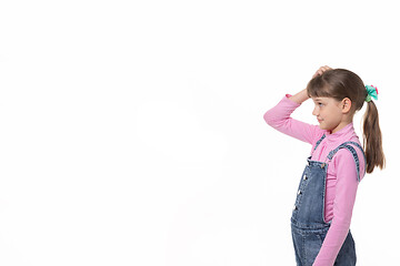 Image showing The girl puzzled scratches her head and looks at an empty spot in the frame.