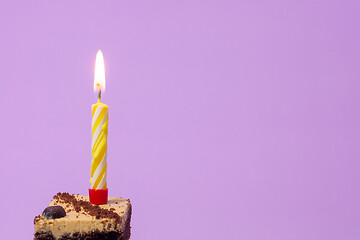 Image showing Festive burning candle on a cake on a light purple background