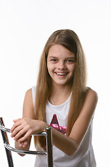 Image showing Girl sitting on a high-backed chair and smiling joyfully