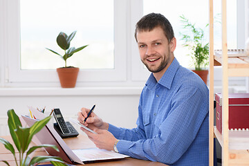 Image showing Young successful businessman writes in a notebook and looked into the frame