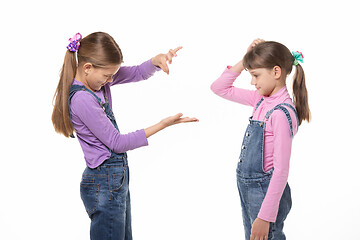 Image showing A girl shows a virtual object on her hand, another girl looks at her and scratches her head in bewilderment.