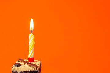 Image showing Festive burning candle on a cake on a bright red background