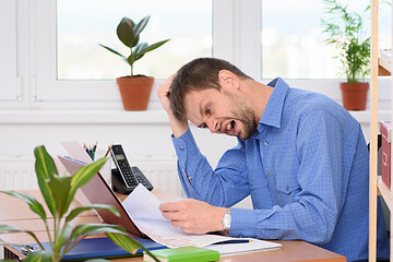 Image showing The office employee is looking at paper documents in horror