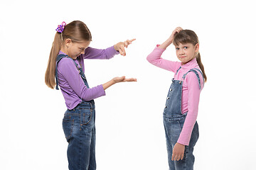 Image showing A girl shows a virtual object on her hand, another girl scratches her head in bewilderment