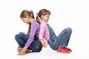 Image showing Children sitting on the floor have fun pushing their backs, isolated on white background