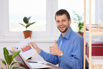 Image showing Young businessman shows charts and thumb up