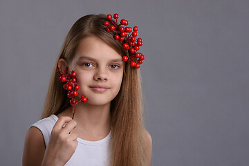 Image showing Portrait of a beautiful ten year old girl with a bunch of berries in her hand and hair