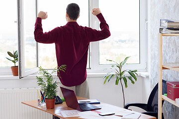 Image showing Office worker does gymnastics standing by the window