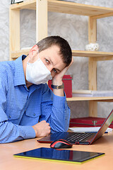 Image showing Sad leader sits behind a worker in front of a laptop wearing a protective mask