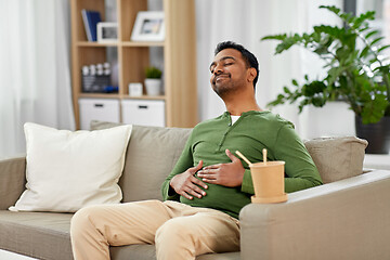 Image showing pleased indian man eating takeaway food at home