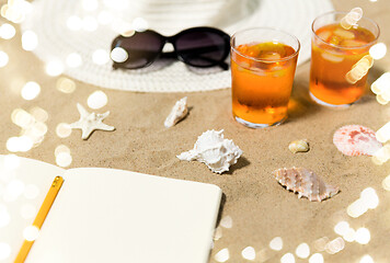 Image showing notebook, cocktails, hat and shades on beach sand