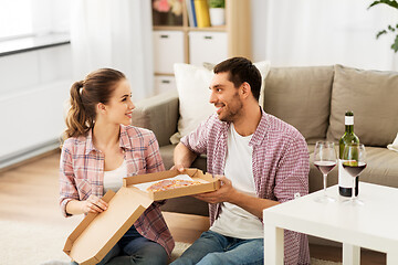 Image showing couple with wine eating takeaway pizza at home