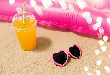 Image showing sunglasses, juice and pool mattress on beach sand